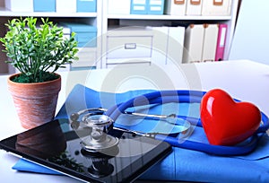 Doctor coat with medical stethoscope and red heart on the desk