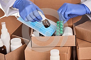 Doctor collecting sets of prescribed medication and supplies into boxes