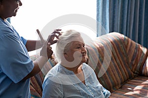 Doctor combing hair of patient in nursing home