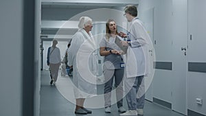 Doctor comes to nurse and elderly woman in clinic corridor