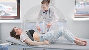 Doctor conducting abdominal examination on female patient in hospital room