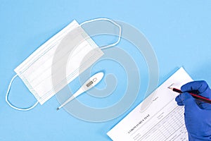 A doctor is conducting a coronovirus test. Doctor`s hands with mask and thermometer on a blue background