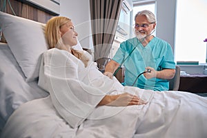 Doctor conducting physical examination of female patient during ward round