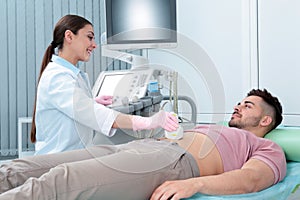 Doctor conducting ultrasound examination of patient`s abdomen