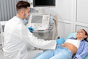 Doctor conducting ultrasound examination of patient`s abdomen