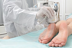 Doctor conducting ultrasound examination of patient`s foot in clinic