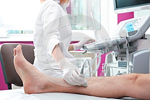 Doctor conducting ultrasound examination of patient`s leg in clinic