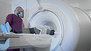 The doctor conducts an MRI or PET scan of a patient in a modern clinic. Girl on the bed inside a 3D scan machine. The