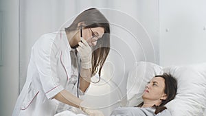 The doctor conducts a routine examination of a patient in a hospital ward. Woman listening the patient with stethoscope