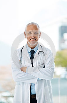 Doctor, confidence and portrait of mature man in a hospital at cardiology clinic with arms crossed. Professional