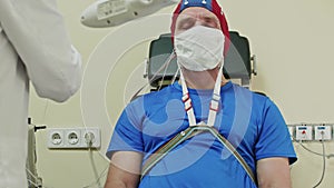 Doctor connects cables to funny cap on patient to start EEG. Examination at doctors