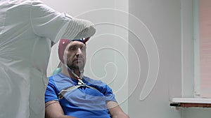 Doctor connects sensors to EEG cap on head of patient who came for examining.