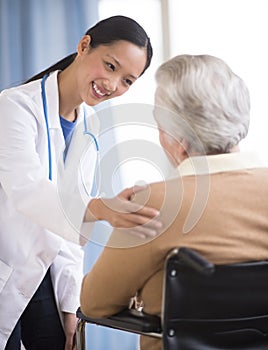 Doctor Consoling Senior Woman Sitting In Wheelchair