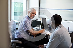 Doctor In Consultation With Male Patient In Office