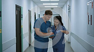 Doctor consulting colleague woman in hospital. Medical team analysing report.