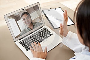 Doctor consulting indian woman patient by online video call on laptop screen.