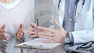 Doctor consulting patient with clipboard and a pen in his hand in medical office. Trust concept in Medicine