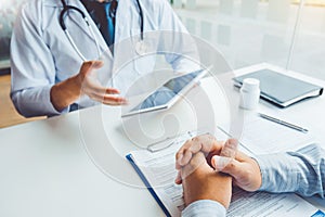 Doctor consulting with patient presenting results on digital tablet tablet sitting at table