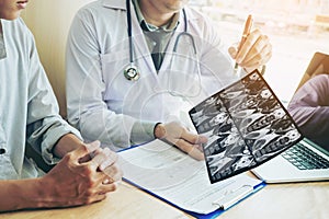 Doctor consulting with patient presenting results on x-ray film