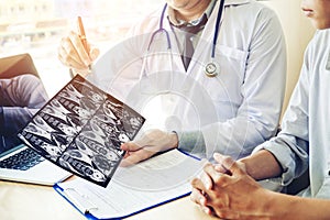 Doctor consulting with patient presenting results on x-ray film