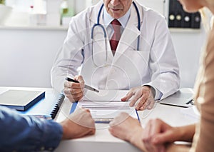 Doctor consulting prognosis with young couple photo