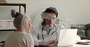 Doctor consulting to older female patient using laptop