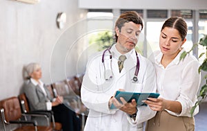Doctor consulting young female patient filling medical form