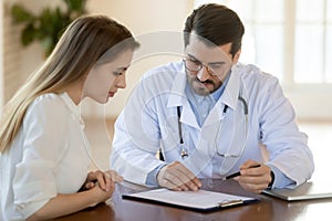 Doctor consulting young woman about insurance contract terms or prescriptions