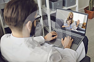 Doctor consults a woman with a child using a computer web camera in the office of a medical clinic.