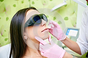 Doctor cosmetologist conducts the procedure of laser hair removal from the body of a girl. Laser hair removal. Cosmology