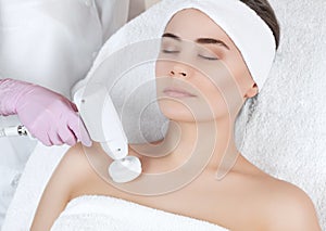 The doctor-cosmetologist makes the apparatus a procedure of Hardware decollete face cleaning with a soft rotating brush photo