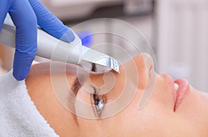 The doctor-cosmetologist makes the apparatus a procedure of ultrasound cleaning of the facial skin