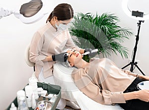 Doctor cosmetologist makes the apparatus a procedure of ultrasound cleaning of the facial skin in a beauty salon. Cosmetology and