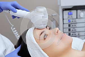 The doctor-cosmetologist makes the Cryotherapy procedure of the facial skin of a beautiful, young woman in a beauty salon.