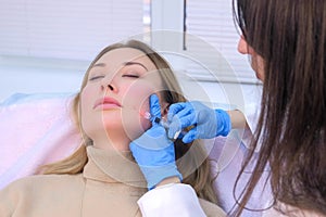 Doctor cosmetologist makes injection with filler in woman face against wrinkles.