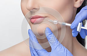 The doctor cosmetologist makes Lip augmentation procedure of a beautiful woman in a beauty salon