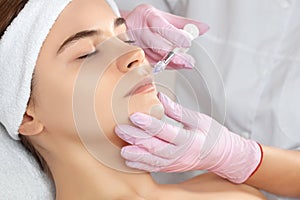 The doctor cosmetologist makes Lip augmentation procedure of a beautiful woman in a beauty salon. Prp therapy, anti wrinkle and