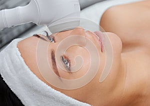 The doctor-cosmetologist makes the procedure Cryotherapy of the facial skin of a beautiful, young woman in a beauty salon.