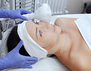 The doctor-cosmetologist makes the procedure Cryotherapy of the facial skin of a beautiful, young woman in a beauty salon.