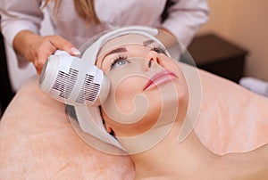 The doctor-cosmetologist makes the procedure Cryotherapy of the facial skin of a beautiful, young woman in a beauty salon