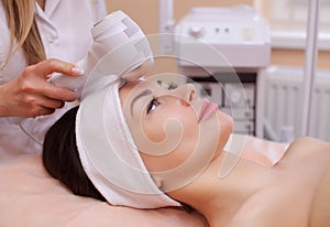 The doctor-cosmetologist makes the procedure Cryotherapy of the facial skin of a beautiful, young woman in a beauty salon.