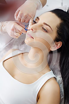 The doctor-cosmetologist makes the procedure Microcurrent therapy of the facial skin of a beautiful, young woman in a beauty