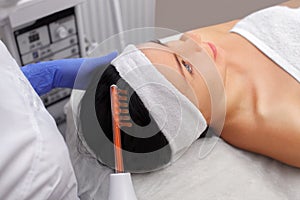 The doctor-cosmetologist makes the procedure Microcurrent therapy On the hair of a beautiful, young woman in a beauty salon photo