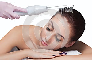 The doctor-cosmetologist makes the procedure Microcurrent therapy On the hair of a beautiful, young woman in a beauty salon