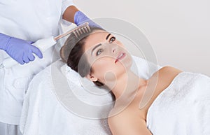 The doctor-cosmetologist makes the procedure Microcurrent therapy On the hair of a beautiful, young woman in a beauty salon.