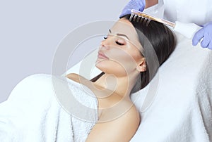 The doctor-cosmetologist makes the procedure Microcurrent therapy On the hair of a beautiful, young woman in a beauty salon