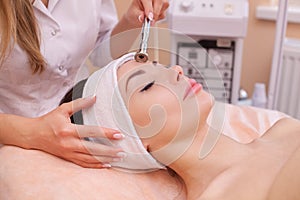 The doctor-cosmetologist makes the procedure Microdermabrasion of the facial skin of a beautiful, young woman