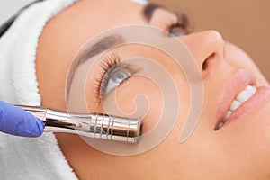 The doctor-cosmetologist makes the procedure Microdermabrasion of the facial skin of a beautiful, young woman in a beauty salon.