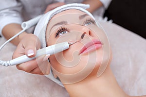 The doctor-cosmetologist makes the procedure treatment of Couperose of the facial skin of a beautiful, young woman