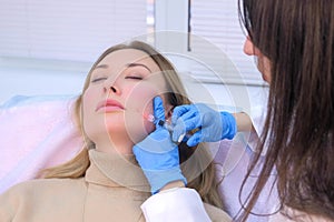 Doctor cosmetologist makes injection with filler in woman face against wrinkles. photo